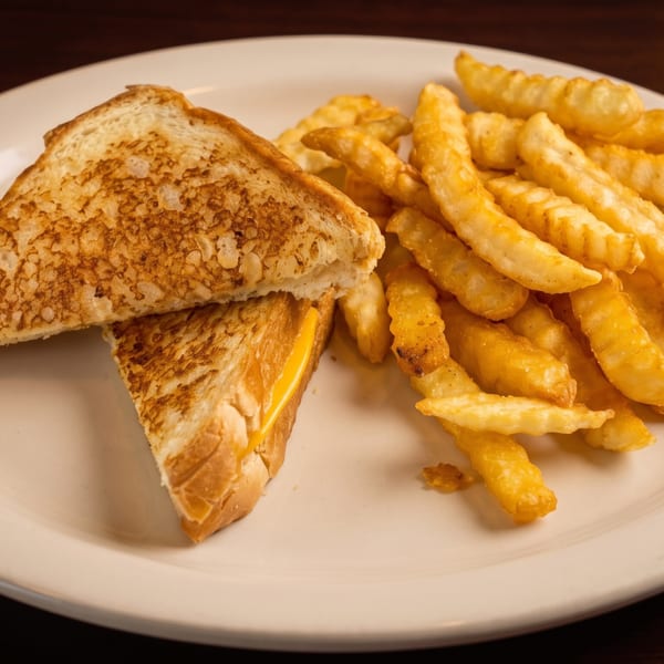 Grilled cheese sandwich cut in half with crinkle-cut fries on a white plate.